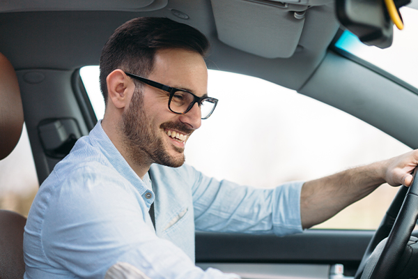 Smiling man with glasses inside a car
