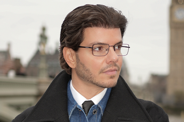 Man with glasses standing outside in a smart outfit